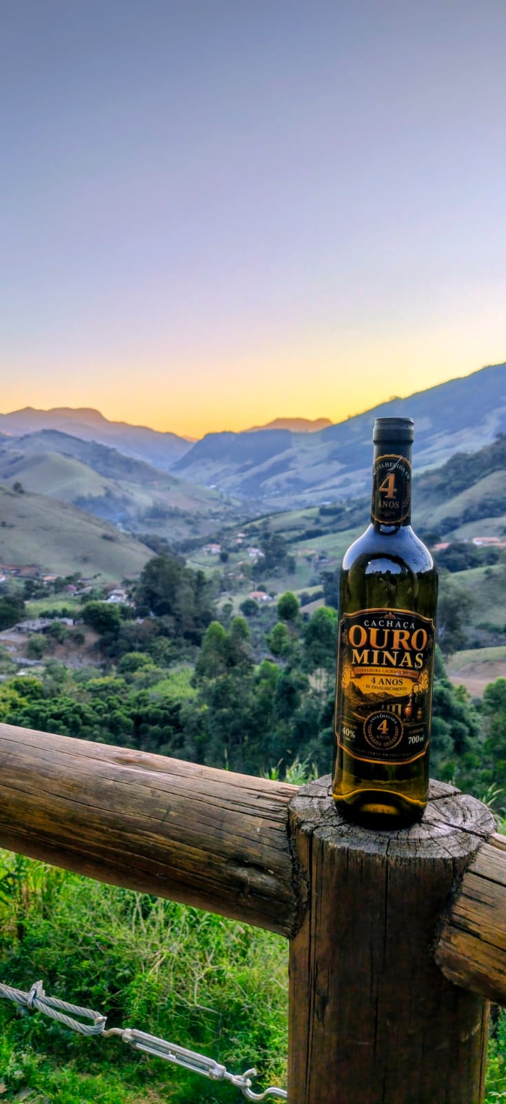 Garrafa de Cachaça Ouro Minas diante das montanhas do Sul de Minas Gerais